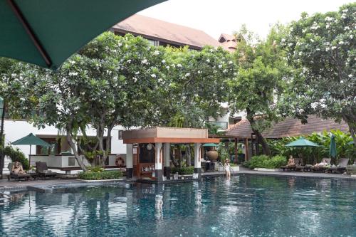 a swimming pool at a resort with trees and a building at RatiLanna Riverside Spa Resort in Chiang Mai