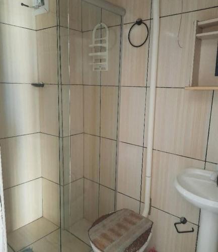 a shower with a glass door next to a sink at Sobrados pertinho do mar in Tramandaí