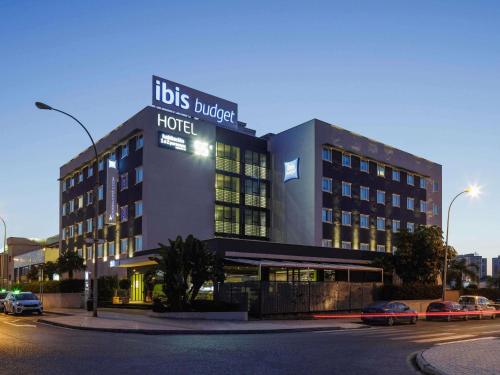a hotel building with cars parked in front of it at Ibis Budget Málaga Aeropuerto Avenida de Velazquez in Málaga