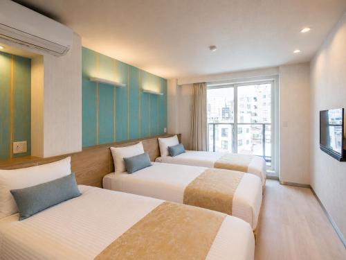 a hotel room with three beds and a window at Hotel SAILS in Tokyo