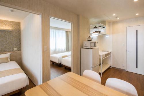 a small hotel room with two beds and a refrigerator at Hotel SAILS in Tokyo