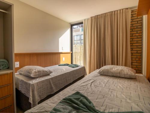 two beds in a hotel room with a window at Villa 18 Atins Rooftop com piscina in Barreirinhas