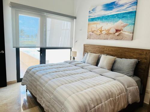 a bedroom with a bed and a painting on the wall at Navela oceanfront apartment in Telchac Puerto