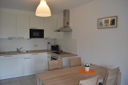 a kitchen with white cabinets and a wooden table at Wangeroogeweg 27 in Schillig