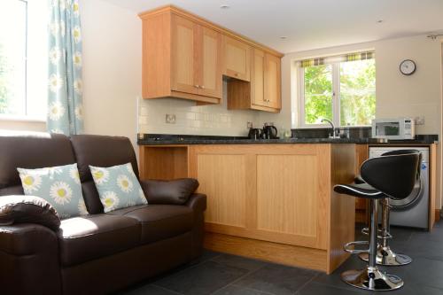 a living room with a couch and a kitchen at Cedar Tree Cottage in Clocaenog