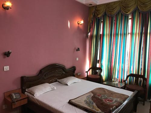 a bedroom with a bed with pink walls and windows at Hotel D R International in Ambāla