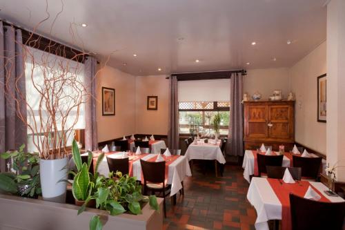 un restaurant avec des tables blanches, des chaises et des plantes dans l'établissement La Boîte à Sel, à Vogelsheim