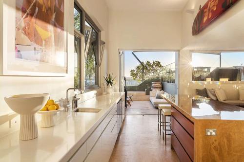 a kitchen with a sink and a counter with a table at Hastings Park: Lavish Ocean Vista Luxury in Noosa Heads