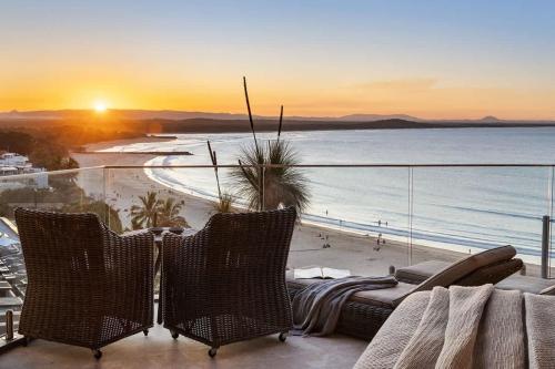 a balcony with a view of the beach at sunset at Hastings Park: Lavish Ocean Vista Luxury in Noosa Heads