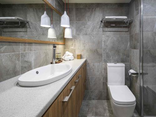 a bathroom with a white sink and a toilet at The Sebel Pinnacle Valley in Merrijig