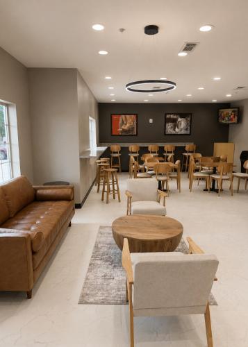 a waiting room with a couch and tables and chairs at Super 8 by Wyndham Brenham TX in Brenham