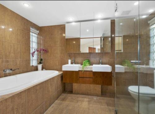 a bathroom with two sinks and a tub and a toilet at Bugalmaa - Cotton Beach in Casuarina