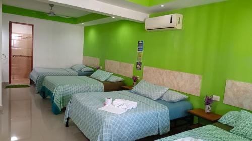 three beds in a room with green walls at Posada Nacha`n - Ka`an in Palenque