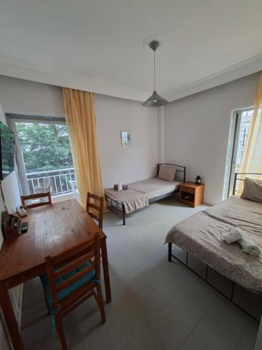 a room with two beds and a table and a window at Beachfront apartment 10m from the beach in Paralia Dionysiou