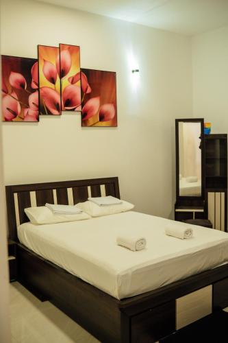a bedroom with a bed with four paintings on the wall at US Apartment in Nochchiyagama