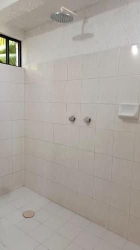 a white tiled bathroom with a shower with a toilet at Posada Nacha`n - Ka`an in Palenque