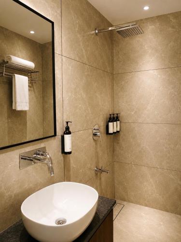 a bathroom with a white sink and a shower at The Sapphire Hotel in Belgaum