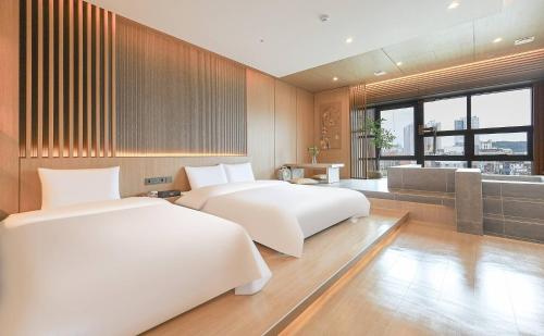 two white beds in a room with a view at ALMOND Hotel in Jinju