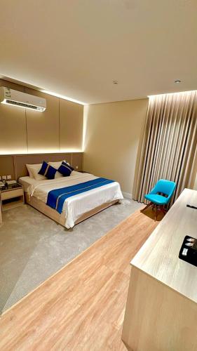 a bedroom with a bed and a blue chair at شقق ركن تالا للشقق المفروشة - اقتصادي in Buraydah