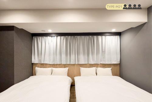 two beds in a room with a window at Luma Urban Hotel 高田馬場 in Tokyo