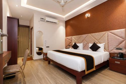 a hotel room with a large bed and a chair at Hotel G Grand Inn in Thanjāvūr