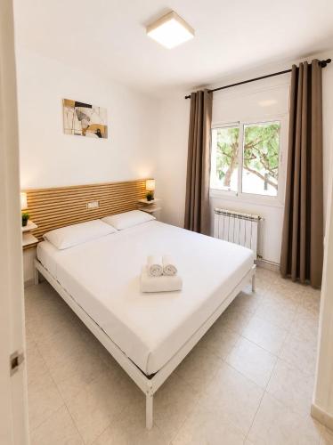 a bedroom with a large white bed with two rings on it at Apartamentos Baymar Playa de Aro in Platja d'Aro