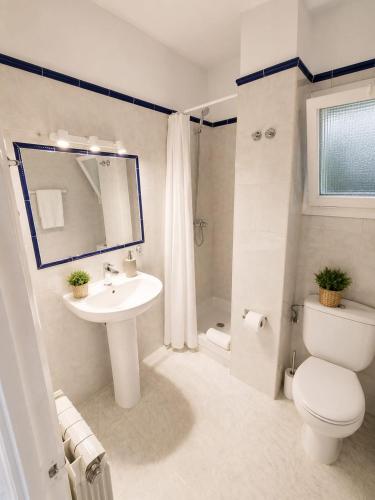 a white bathroom with a sink and a toilet at Apartamentos Baymar Playa de Aro in Platja d'Aro