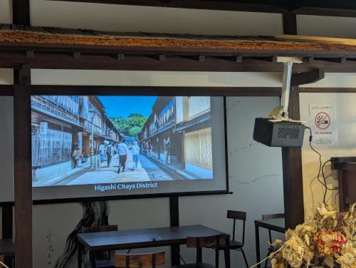 a projection screen with a picture of a street at Yuimaru EAST - 最大18名貸切OK in Kanazawa