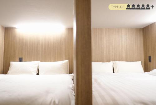 two beds in a hotel room with white pillows at Luma Urban Hotel 高田馬場 in Tokyo