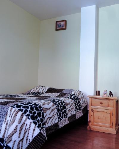a bedroom with a bed and a wooden night stand at Alojamiento Primer Piso Confort Riobamba in Riobamba