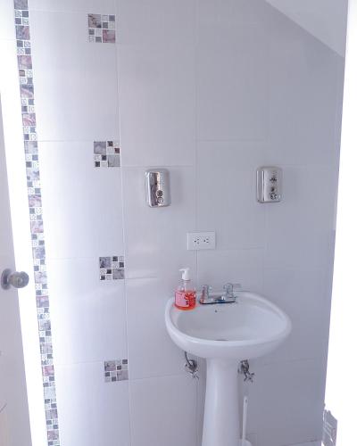 a white bathroom with a sink and a shower at Alojamiento Primer Piso Confort Riobamba in Riobamba