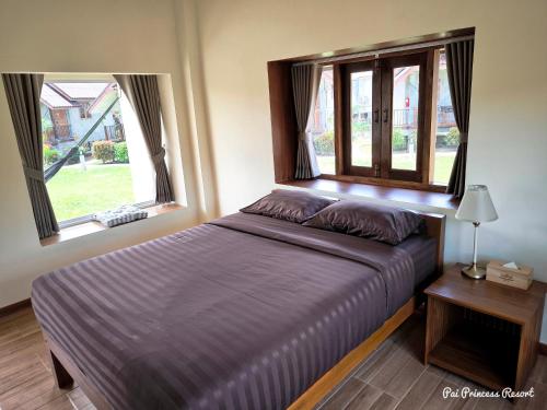 a bed in a bedroom with two windows at Pai Princess Resort in Pai
