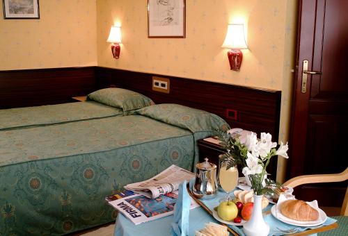 ein Hotelzimmer mit einem Bett und einem Tisch mit Essen in der Unterkunft Hotel Leonardo Da Vinci in Sassari