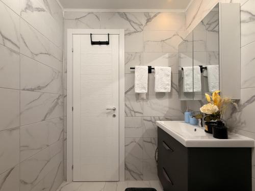 a white bathroom with a sink and a mirror at Olive Apartment Cosmopolis in Tunari