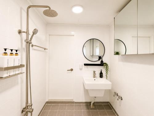 a white bathroom with a sink and a mirror at TOV stay in Seoul