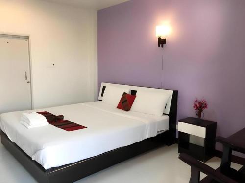 a bedroom with a large white bed with a cross on the wall at Nan Treasure Hotel in Ban Hua Wiang Nua