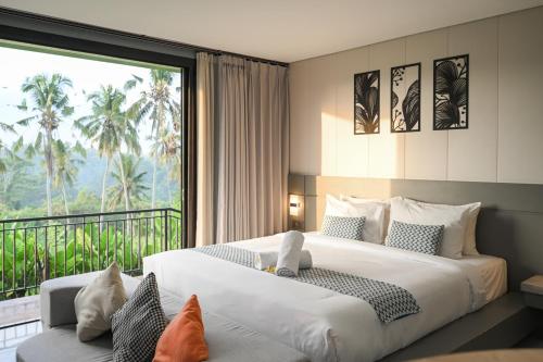a bedroom with a large bed and a large window at Root and Rise Cabins in Tabanan