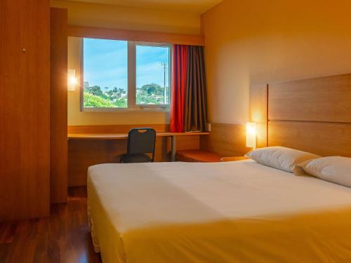 a hotel room with a bed and a window at ibis Novo Hamburgo in Novo Hamburgo