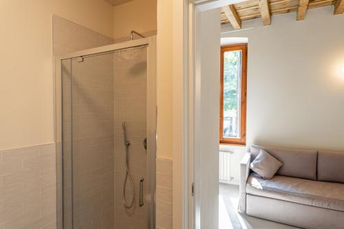 a bathroom with a glass shower with a couch at Montenero City Rooms in Verona