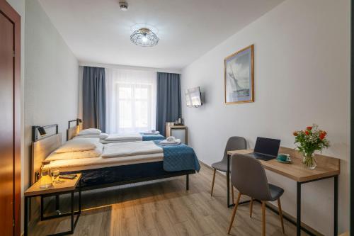 a bedroom with a bed and a desk with a laptop at Apartamenty Pod Lwem in Świdnica