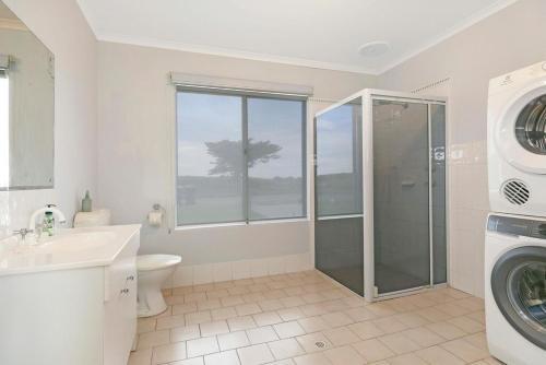 a bathroom with a shower and a washing machine at Tahren Beach Getaway in Middleton