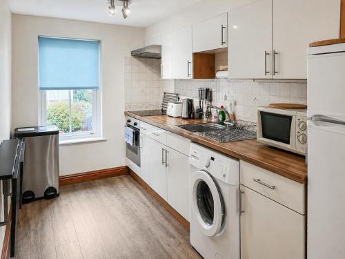 a kitchen with white cabinets and a washer and dryer at Howgills Apartment 9 - Ukc9724 in Sedbergh