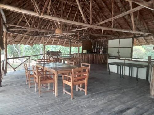 a dining room with wooden tables and chairs at At the river campsite in Kihihi