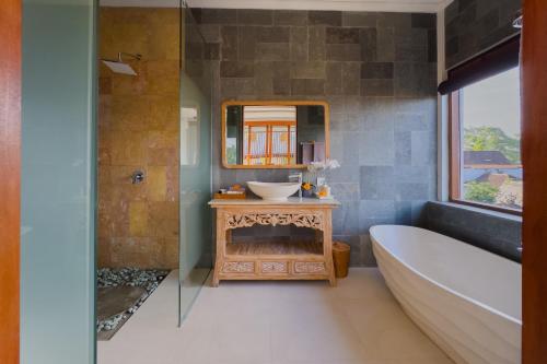 a bathroom with a tub and a sink and a mirror at Santosha Place in Ubud