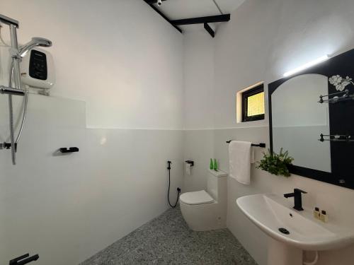 a white bathroom with a sink and a toilet at Wihara Cottage Sigiriya in Sigiriya