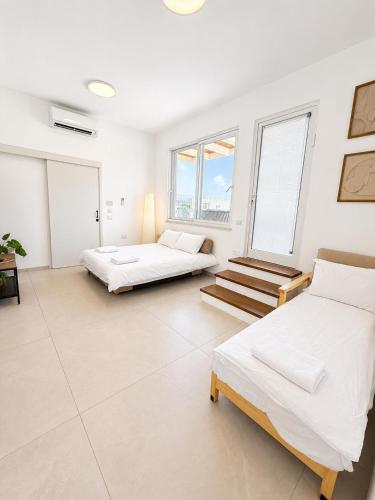 two beds in a room with white walls and windows at פלג טל -דפנה in Dafna