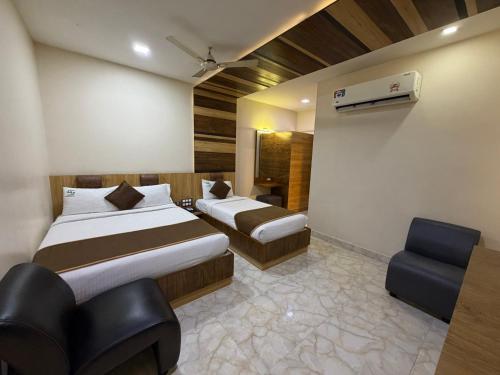 a hotel room with two beds and a chair at Hotel Sai Krish Grand Pallavaram in Chennai