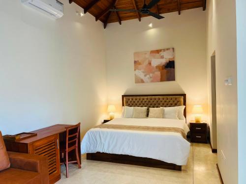 a bedroom with a bed and a desk with two lamps at Eden Collection Thalpe in Talpe