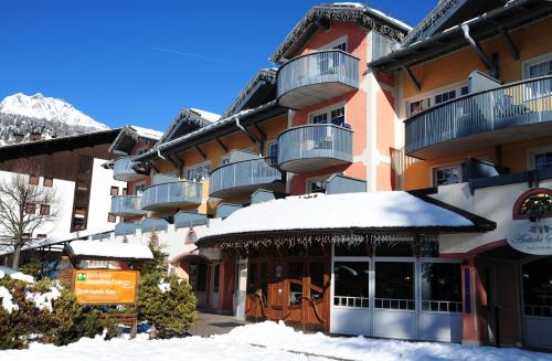 a building with snow on the ground in front of it at Sporting Aparthotel in San Martino di Castrozza