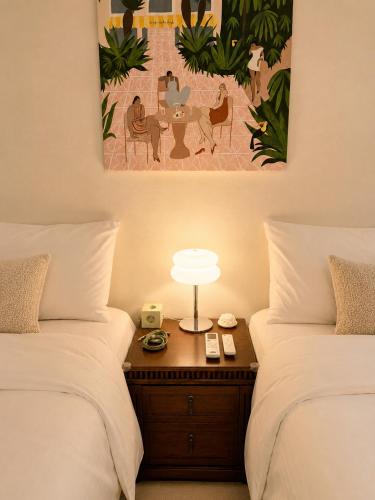 a bedroom with two beds and a table with a lamp at Maison de Jann in Seoul